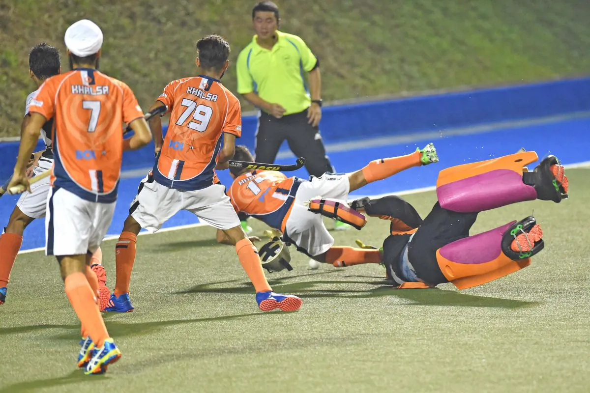 Khalsa-A’s Inderpal Singh falls as the SSSC-A goalie dashes from his goal to stop the attack. A penalty stroke was awarded from which Khalsa reduced the deficit to 2-3, in their HKHA Premier Division match at King’s Park on Sunday Dec 4. The match ended 3-3.(Bill Cox/Epoch Times)