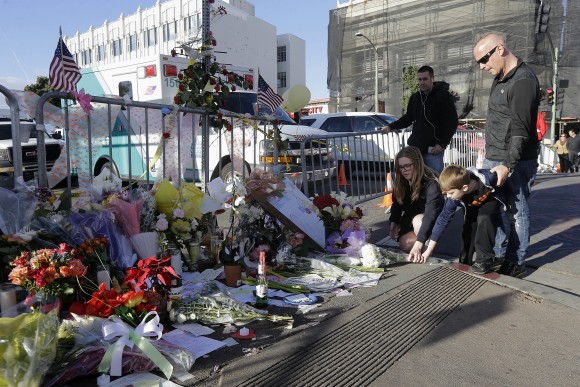 Luke Dollar, right, watches as his children Alexis, 10, and Dominic, 7, leave flowers at a makeshift memorial near the site of a warehouse fire in Oakland, Calif., on Dec. 6, 2016. (AP Photo/Jeff Chiu)
