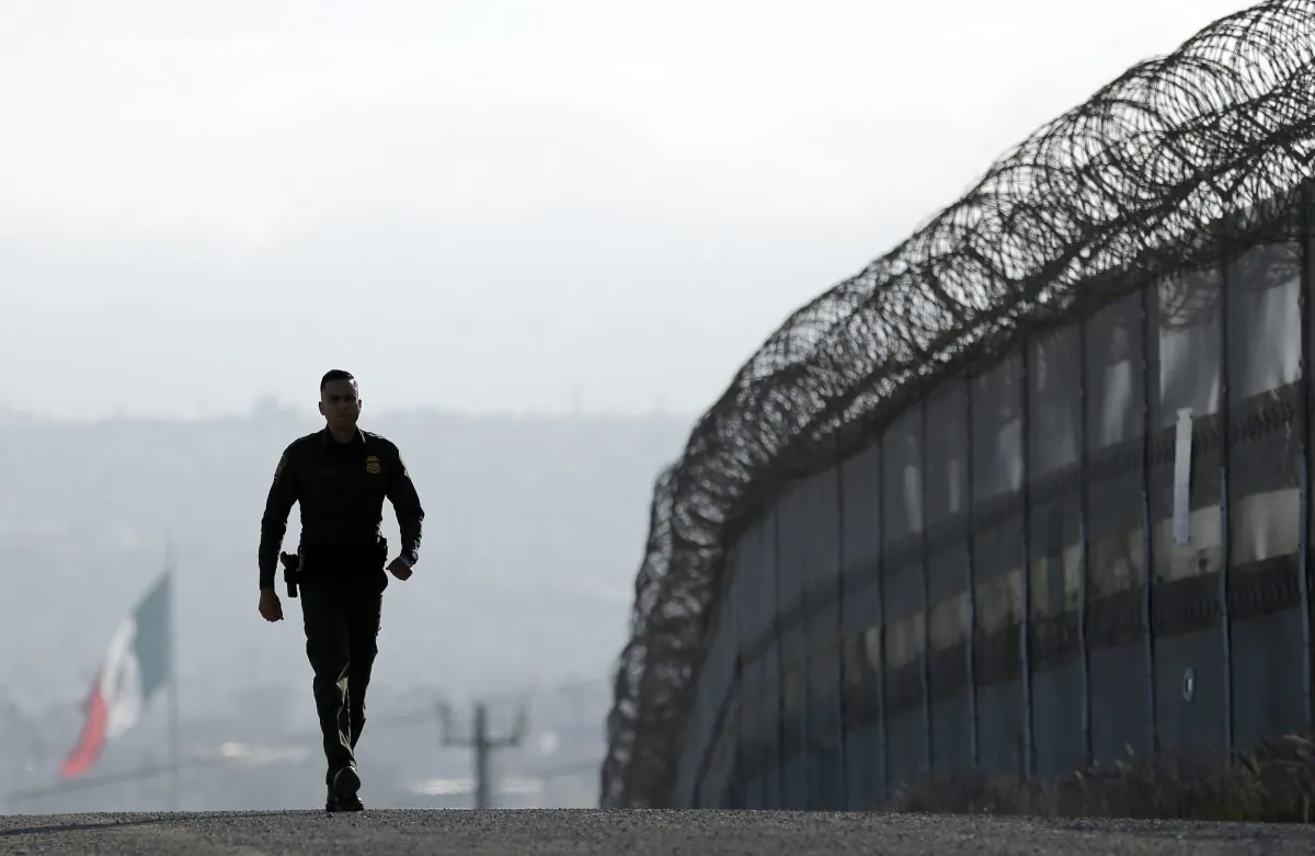 A Border Patrol agent walks near the secondary fence separating Tijuana, Mexico, and San Diego on June 22, 2016. (AP Photo/Gregory Bull, File)