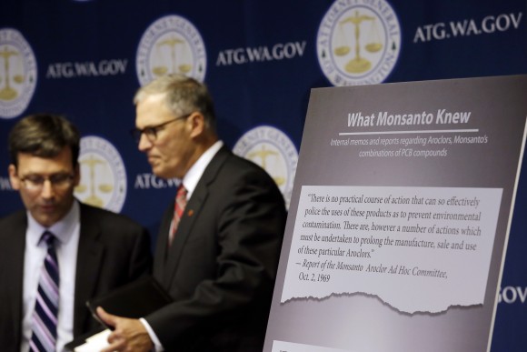 Washington Attorney General Bob Ferguson, left, introduces Gov. Jay Inslee at a news conference where Ferguson announced a lawsuit against agrochemical giant Monsanto over pollution from PCBs, Thursday, Dec. 8, 2016, in Seattle. Washington says it's the first U.S. state to sue Monsanto over pollution from PCBs. The chemicals, polychlorinated biphenyls, were used in many industrial and commercial applications, including in paint, coolants, sealants and hydraulic fluids. PCB contamination impairs rivers, lakes and bays around the country. (AP Photo/Elaine Thompson)