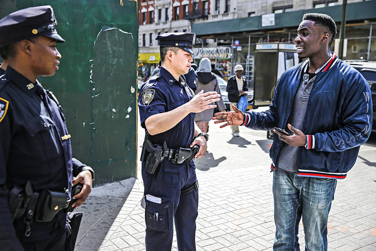 Police officers Max Chow (C) and Shakara President greet a pedestrian on 125th Street in Harlem, New York, on April 29, 2015. (AP Photo/Seth Wenig)
