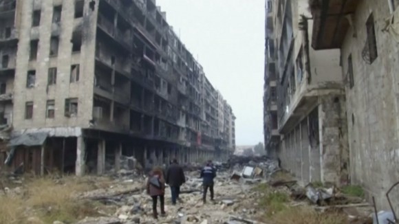 People walking among damaged buildings on a street filled with debris near the ancient Umayyad Mosque, in the Old City of Aleppo on Dec. 13, 2016. (AP Photo)