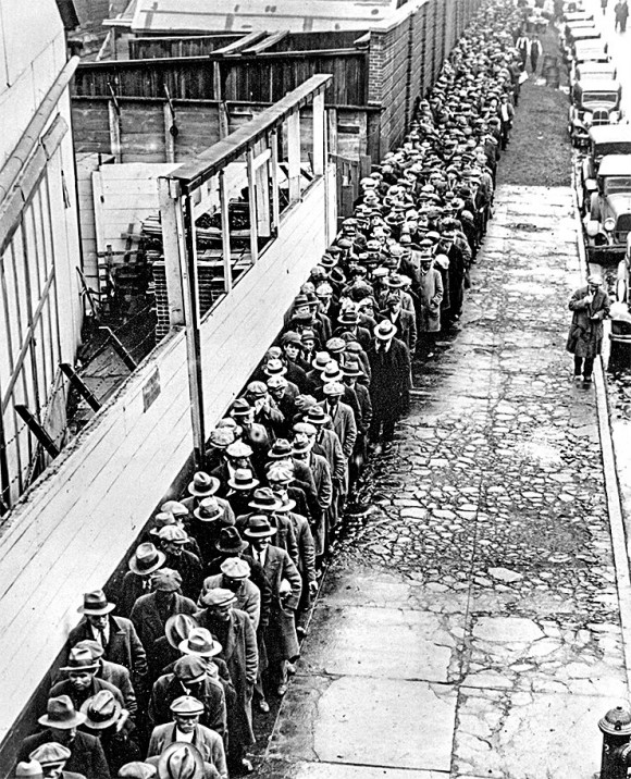 Jobless and homeless men wait to get free dinner at New York's municipal lodging house in the winter of 1932–33. Companies and banks defaulted in droves during the Great Depression because of too much debt, causing a crash in GDP and massive unemployment. 