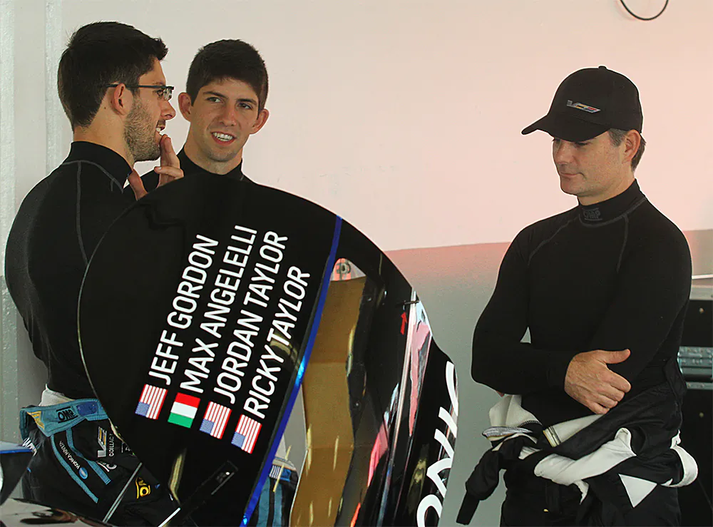 Jordan (L) and Ricky Taylor discuss strategies with NASCAR star Jeff Gordon (R) in the Wayne Taylor Garage at Daytona, Dec. 13, 2016. (Chris Jasurek/Epoch Times)