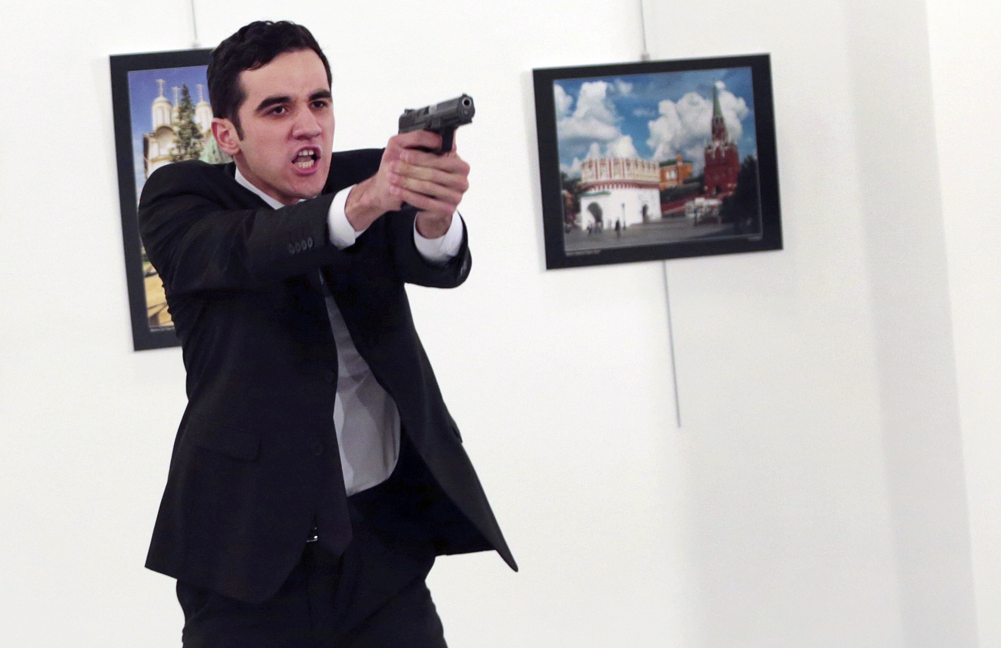 A man identified as Mevlut Mert Altintas holds up a gun after shooting Andrei Karlov, the Russian Ambassador to Turkey, at a photo gallery in Ankara, on Dec. 19, 2016. (AP Photo/Burhan Ozbilici)