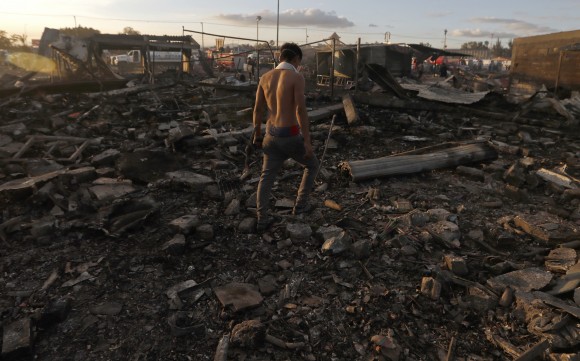 A man walks through the scorched ground of the open-air San Pablito fireworks market, in Tultepec, outskirts of Mexico City, Mexico, Tuesday, Dec. 20, 2016. An explosion ripped through Mexico's best-known fireworks market where most of the fireworks stalls were completely leveled. According to the Mexico state prosecutor there are dozens dead. (AP Photo/Eduardo Verdugo)