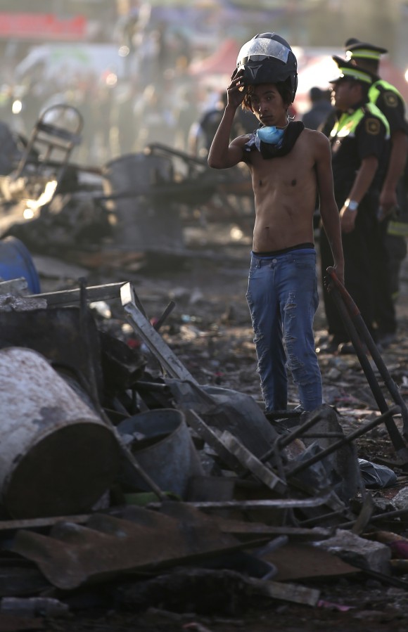 A boy takes his helmet off as he pauses while working at the scorched ground of the open-air San Pablito fireworks market, in Tultepec, outskirts of Mexico City, Mexico, on Dec. 20, 2016. (AP Photo/Eduardo Verdugo)