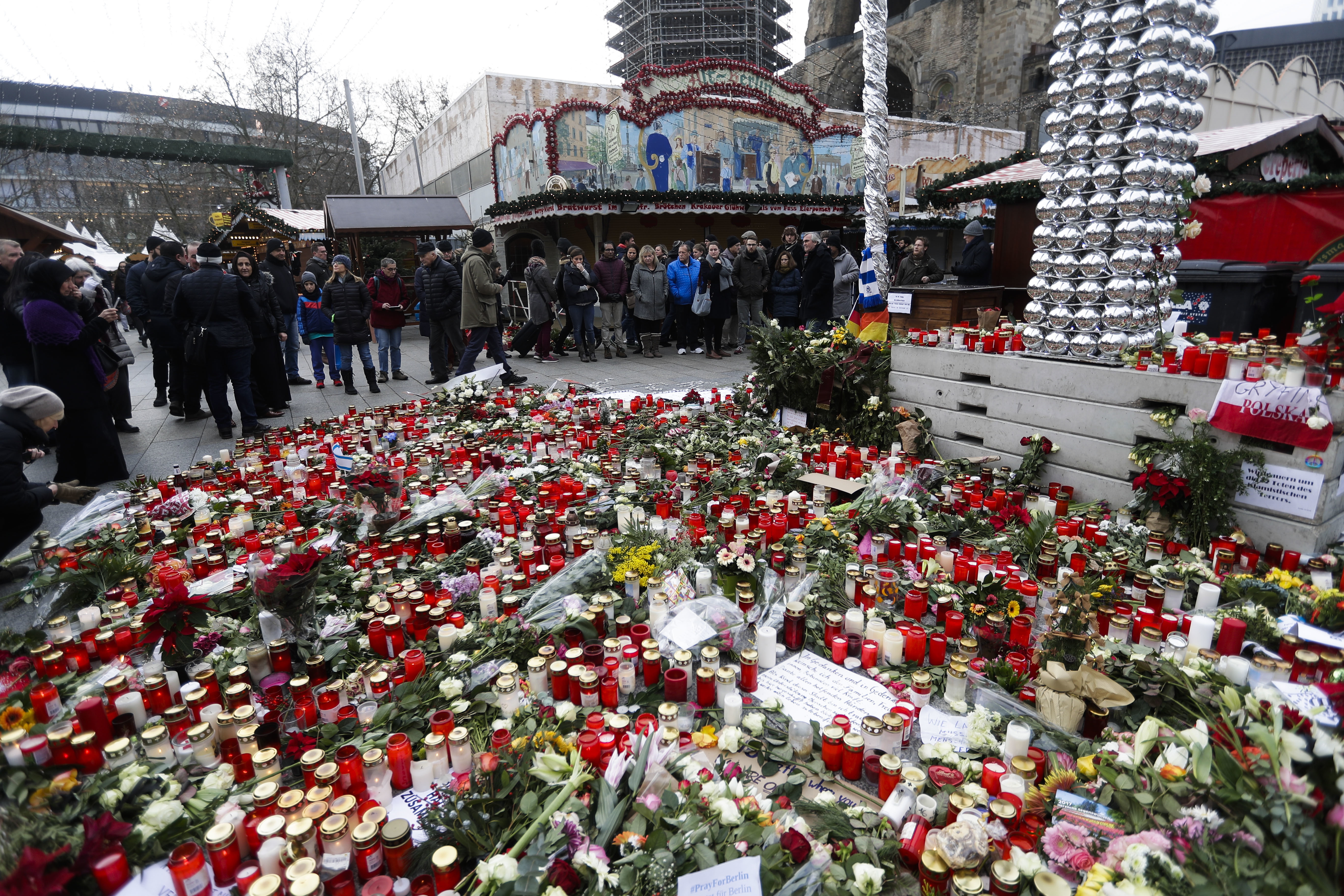 People stand around candles at the reopened Christmas market, three days after a truck ran into the crowd and killed several people, at the Kaiser Wilhelm Memorial Church in Berlin, on Dec. 22, 2016. (AP Photo/Markus Schreiber)