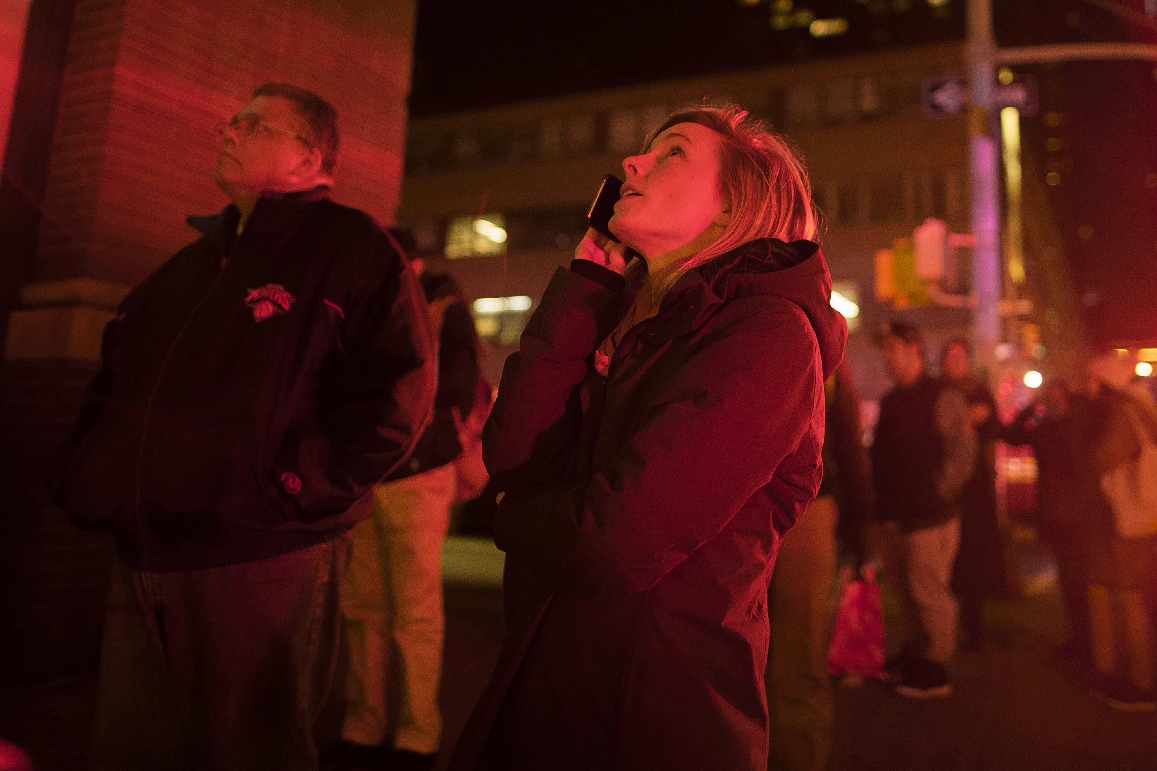 A woman looks at a building fire as she waits to enter the restricted area blocked by the police on the west side of Manhattan in New York on Dec. 22, 2016. (AP Photo/Andres Kudacki)