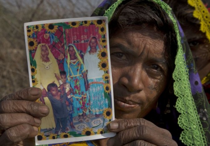 In this photo taken on Thursday, Dec. 1, 2016, Ameri Kashi Kolhi shows picture of her daughter Jeevti, right, in Payro Lundh, Pakistan. The night Jeevti disappeared, her family slept outside to escape Pakistan's brutal summer heat; in the morning she was gone, snatched by a wealthy landlord to whom her parents owed $1,000 dollars. She is one of the estimated 1,000 Christian and Hindu girls taken from their homes every year in Pakistan for supposed repayments of debt, most of them ending up married off to older men and forcibly converted to Islam.(AP Photo/B.K. Bangash)