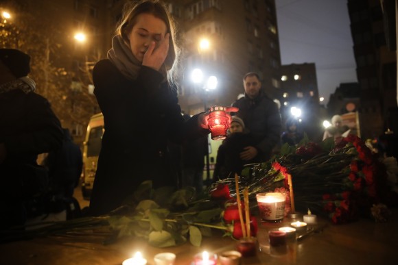 A woman lights a candle at the well-known military choir's building in Moscow, Russia on Dec. 25, 2016. (AP Photo/Pavel Golovkin)