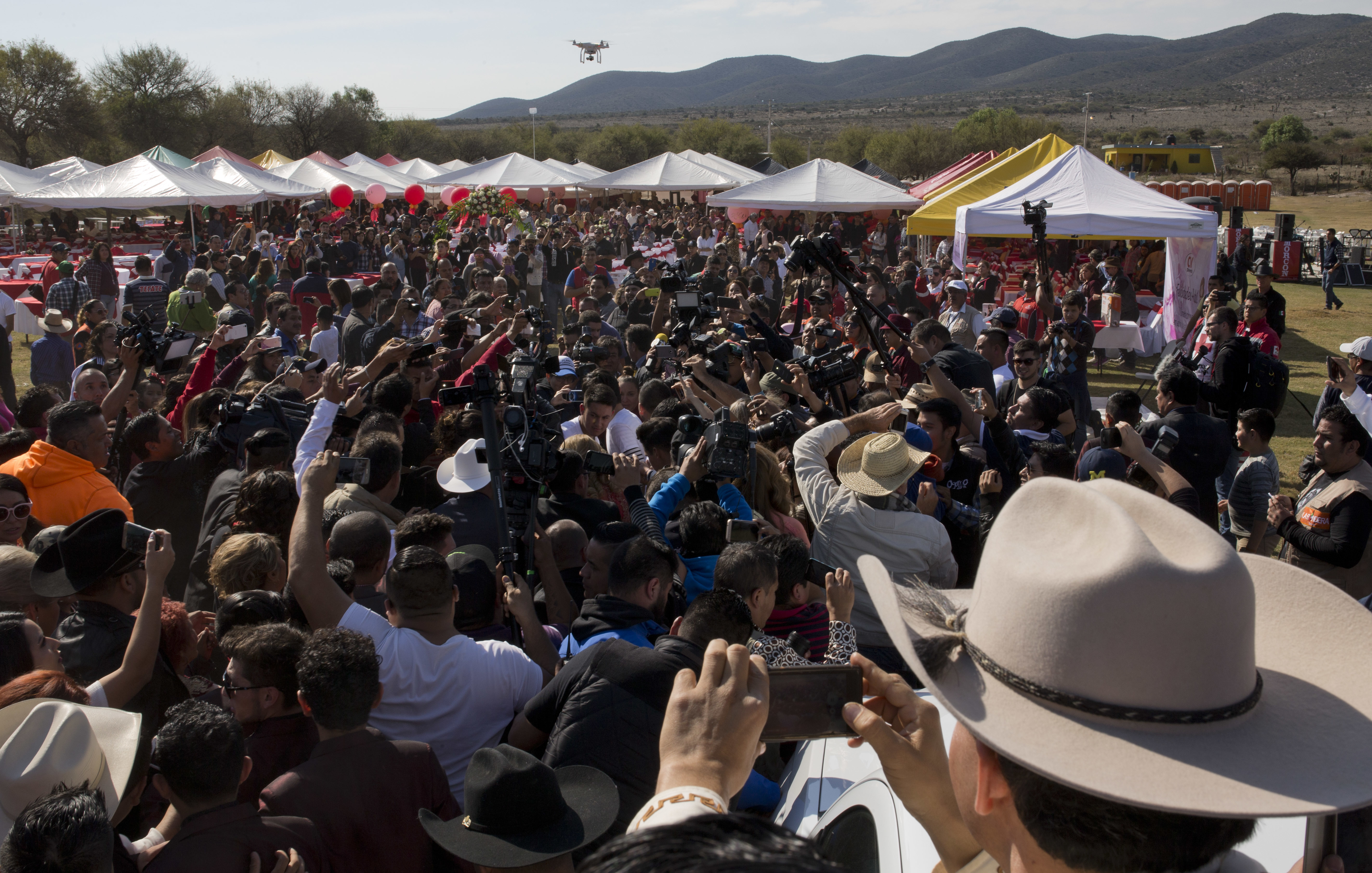 Rubi Ibarra, not seen, arrives at the site of a Mass that is part of her down-home 15th birthday party, surrounded by a horde of journalists and a drone flying overhead, in the village of La Joya, San Luis Potosi State, Mexico, on Dec. 26, 2016. (AP Photo/Enric Marti)
