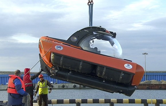 In this Tuesday, Dec. 27, 2016 frame grab made available by Russian Rossiya One TV Channel Emergency Ministry employees unload a submersible to make it ready to join the search for bodies and fragments of the crashed plane, on a pier just outside Sochi, Russia. (Rossiya One TV Channel photo via AP) MANDATORY CREDIT