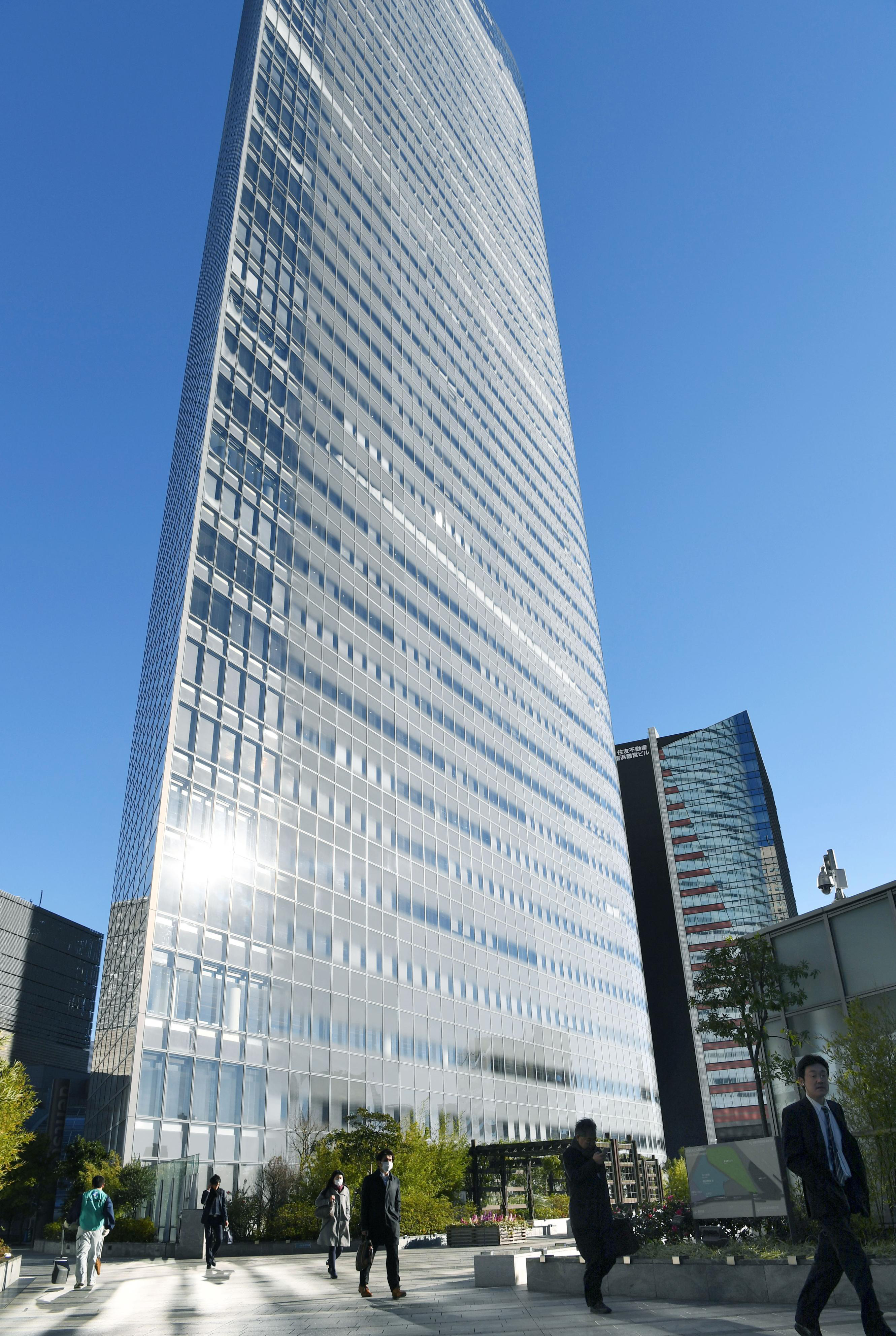 People walk past the headquarters of the top Japanese advertising company Dentsu Inc. in Tokyo on Dec. 28, 2016. (Kyodo News via AP)