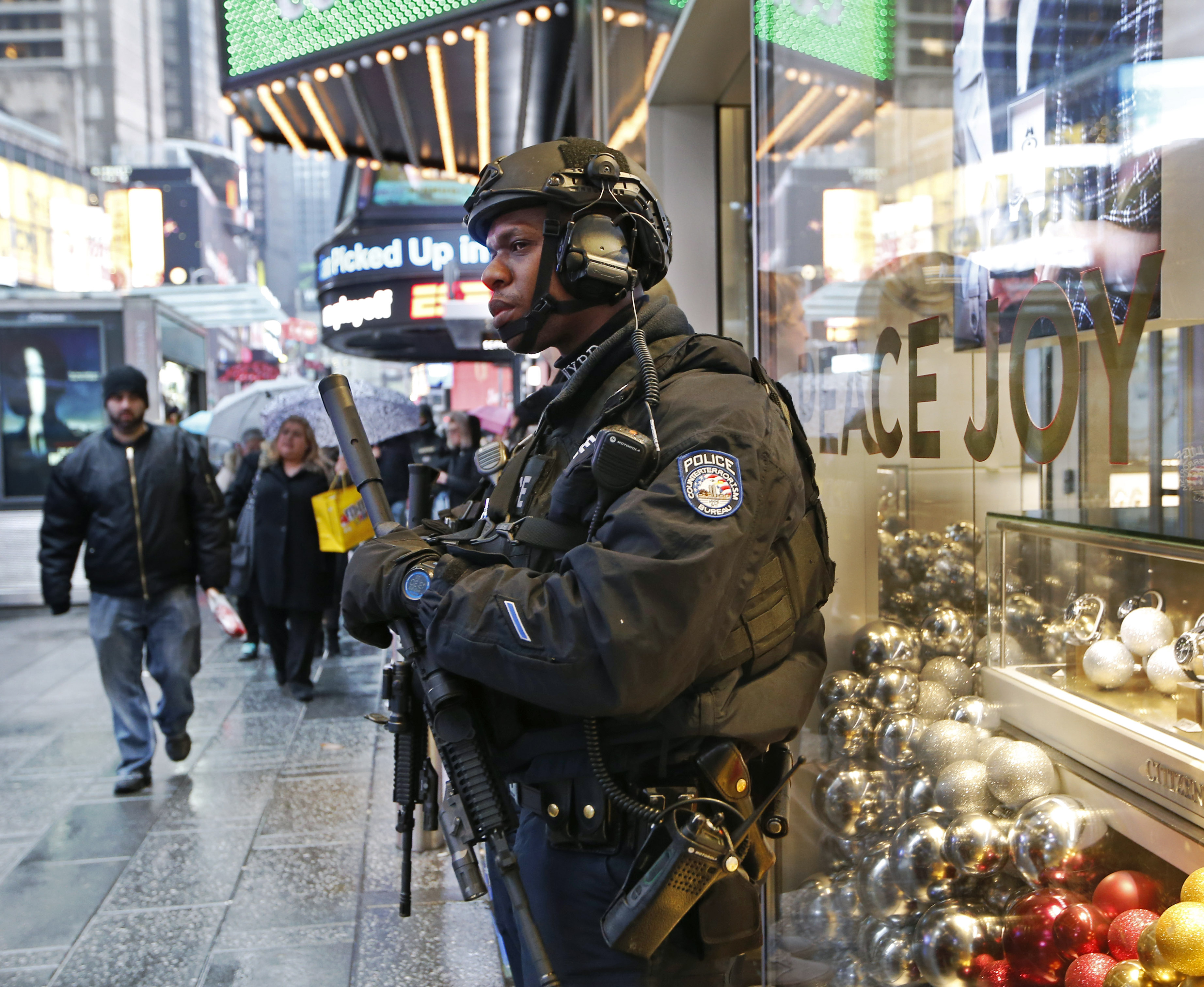 A heavily armed counterterrorism officer takes shelter beneath an overhang above a store in Times Square, on Dec. 29, 2016. (AP Photo/Kathy Willens)