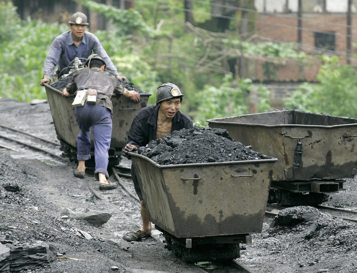 In a file photo, miners push carts containing coal at a mine in Qianwei county, Sichuan. (Liu Jin/AFP/Getty Images)