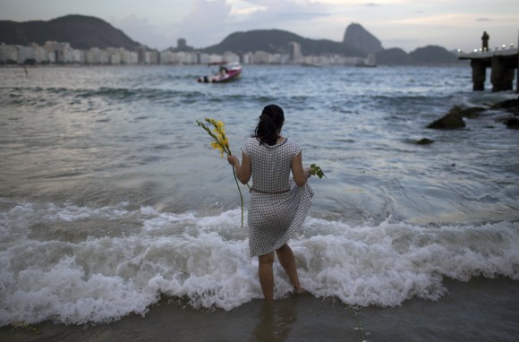 A woman offers flowers to Yemanja, goddess of the sea, for good luck in the coming year during New Year's Eve festivities on Copacabana beach in Rio de Janeiro, Brazil, on Dec. 31, 2016. (AP Photo/Leo Correa)