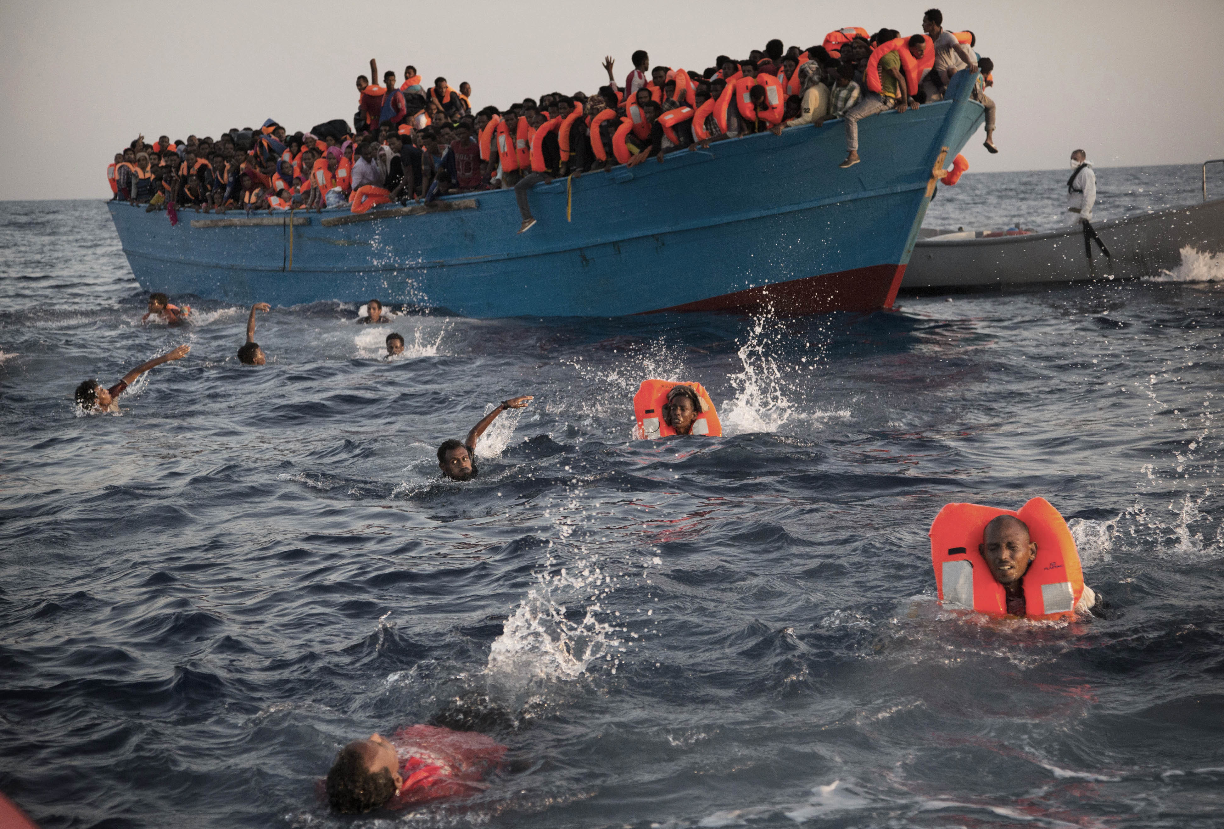 Migrants, most from Eritrea, jump into the water from a crowded wooden boat as they are helped by members of an NGO during a rescue operation in the Mediterranean sea near Libya on Aug. 29, 2016.  (AP Photo/Emilio Morenatti)