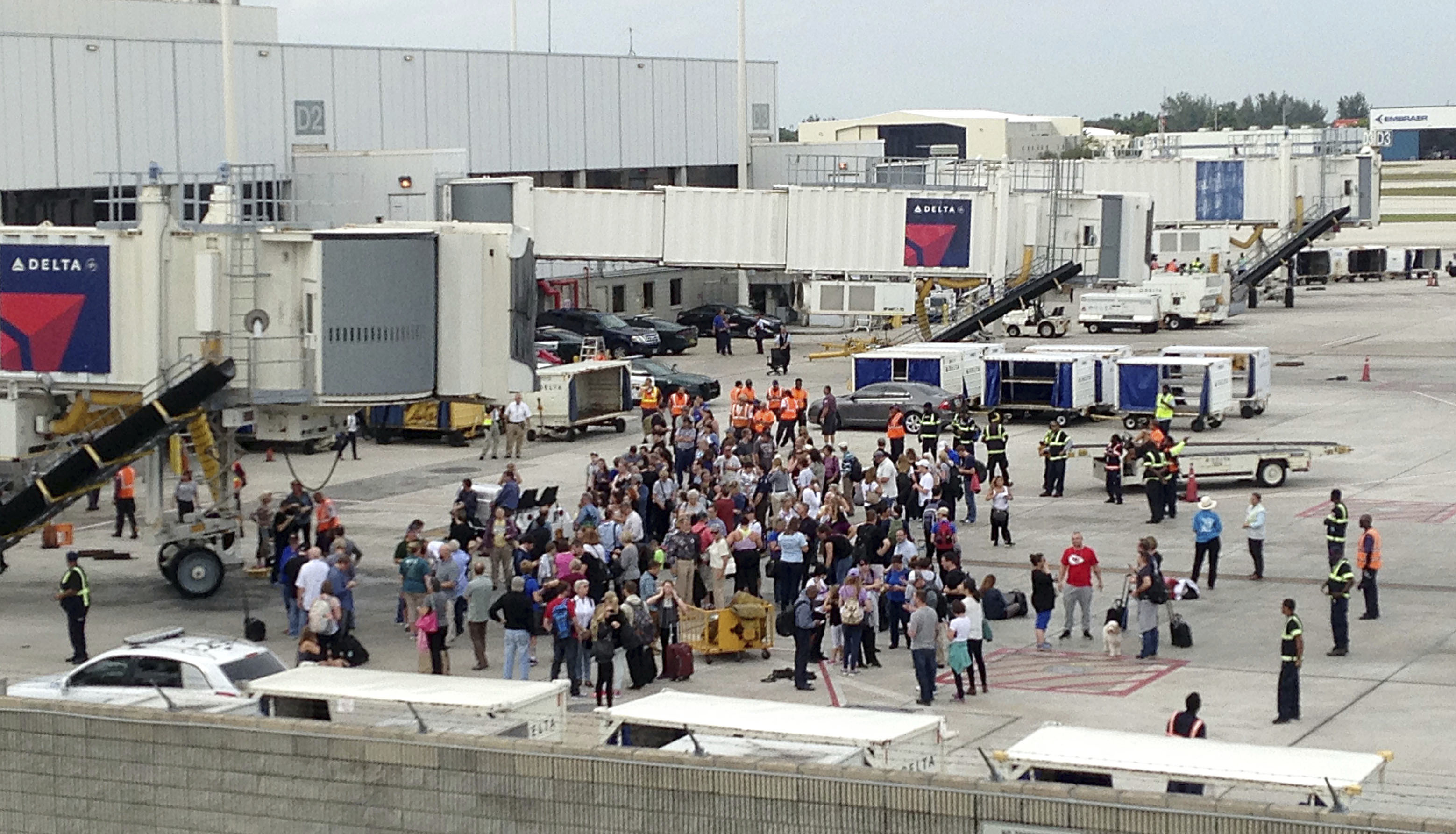 People stand on the tarmac at the Fort Lauderdale-Hollywood International Airport after a shooter opened fire inside a terminal of the airport, killing several people and wounding others before being taken into custody in Fort Lauderdale, Fla., on Jan. 6, 2017. (AP Photo/Wilfredo Lee)