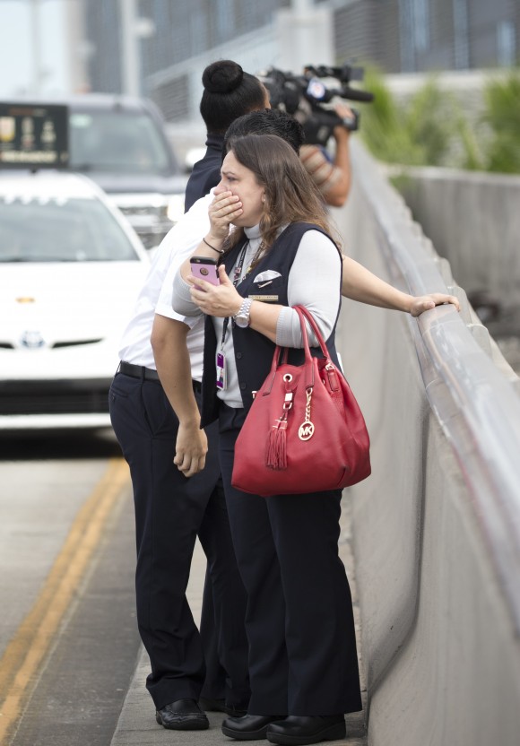 People react at Fort Lauderdale–Hollywood International Airport, Friday, Jan. 6, 2017, in Fort Lauderdale, Fla. A gunman opened fire in the baggage claim area at the airport Friday, killing several people and wounding others before being taken into custody in an attack that sent panicked passengers running out of the terminal and onto the tarmac, authorities said. (AP Photo/Wilfredo Lee)