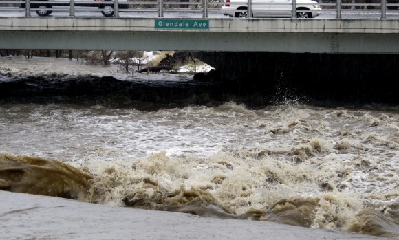 Traffic crosses the raging Truckee River, where it runs near the Grand Sierra hotel-casino along a line that divides the cities of Reno and Sparks, Nev. on Jan. 8, 2017. More than 1,000 homes have been evacuated due to overflowing streams and drainage ditches in the area, which remains under a flood warning through Tuesday. (AP Photo/Scott Sonner)