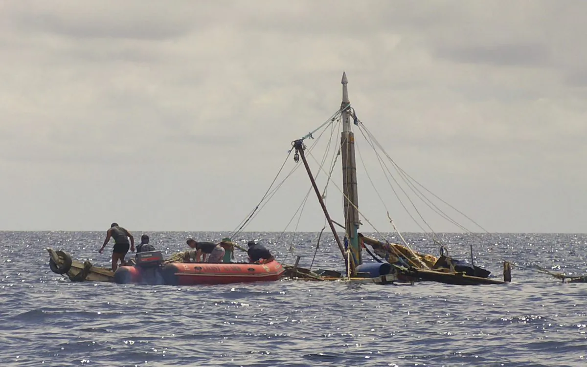 Members of the Philippine Coast Guard, left, approach the almost sunken fishing boat of Filipino fishermen who were killed by suspected pirates in waters near Zamboanga City, southern Philippines Tuesday, on Jan. 10, 2017. (Philippine Coast Guard via AP)