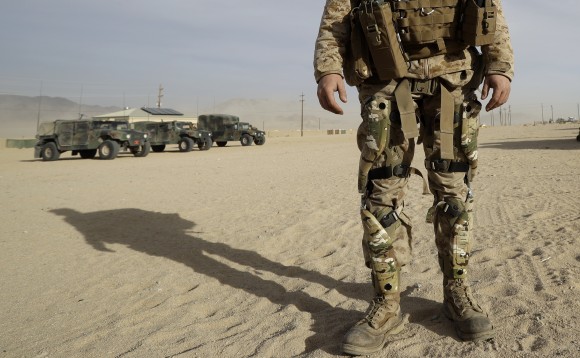A Marine wears knee braces and a backpack that harvest energy from his movements during an exhibition of green energy technology in Twentynine Palms, Calif. on Dec. 7, 2016. (AP Photo/Gregory Bull)