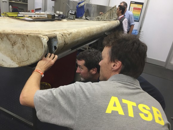 FILE - In this July. 20, 2016, file photo released by the Australian Transport Safety Bureau (ATSB), staff examine a piece of aircraft debris at their laboratory in Canberra, Australia. The flap was found in June 2016 by residents on Pemba Island off the coast of Tanzania and officials had previously said it was highly likely to have come from flight MH370. While search crews spent years trawling in futility through a remote patch of the Indian Ocean for the missing Malaysia Airlines Flight 370, people wandering along beaches on the other side of the ocean began spotting debris that washed ashore. Those pieces provided key information and raised questions whether Malaysia, Australia and China - who funded the hunt for the underwater wreckage - missed key opportunities by failing to organize coastal searches for plane parts. (ATSB via AP, File)