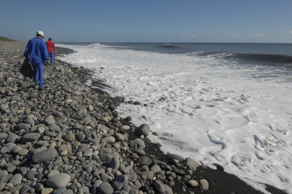 In this file photo, municipal workers search Reunion Island beaches where expected debris of the missing Malaysia Airlines Flight 370 could be washed up onto the shore near Saint-Andre, on the French Island of Reunion. (AP Photo/Fabrice Wislez)