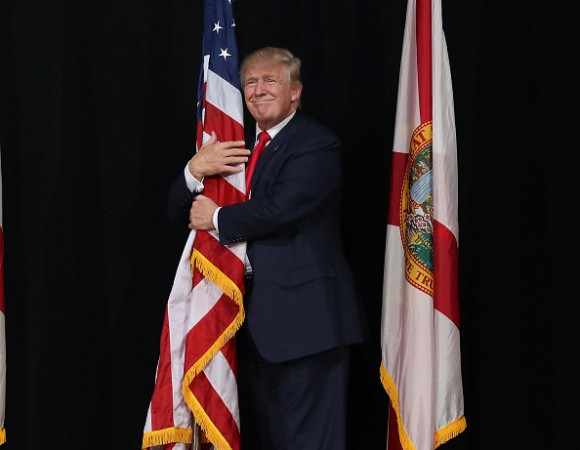 TAMPA, FL - OCTOBER 24: Republican presidential candidate Donald Trump hugs the American flag as he arrives for a campaign rally at the MidFlorida Credit Union Amphitheatre on October 24, 2016 in Tampa, Florida. There are 14 days until the the presidential election. (Photo by Joe Raedle/Getty Images)