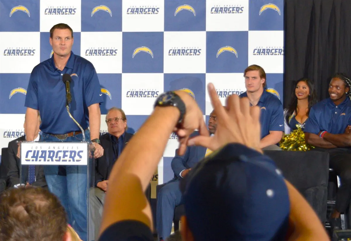 Chargers quarterback Philip Rivers speaks at a rally celebrating the NFL team's move to Los Angeles from San Diego, while a fan forms the letters "LA" with his hands, in Inglewood, Calif. on Jan. 18. (Sarah Le/Epoch Times)