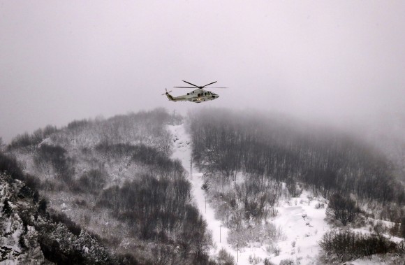 A Finance Police helicopter hovers above the town of Farindola, central Italy, Thursday, Jan. 19, 2017. Days of heavy snowfall had knocked out electricity and phone lines in many central Italian towns and hamlets, compounded by four powerful earthquakes that struck the region on Wednesday, and an avalanche which buried a four-star spa hotel near Farindola. (AP Photo/Gregorio Borgia)