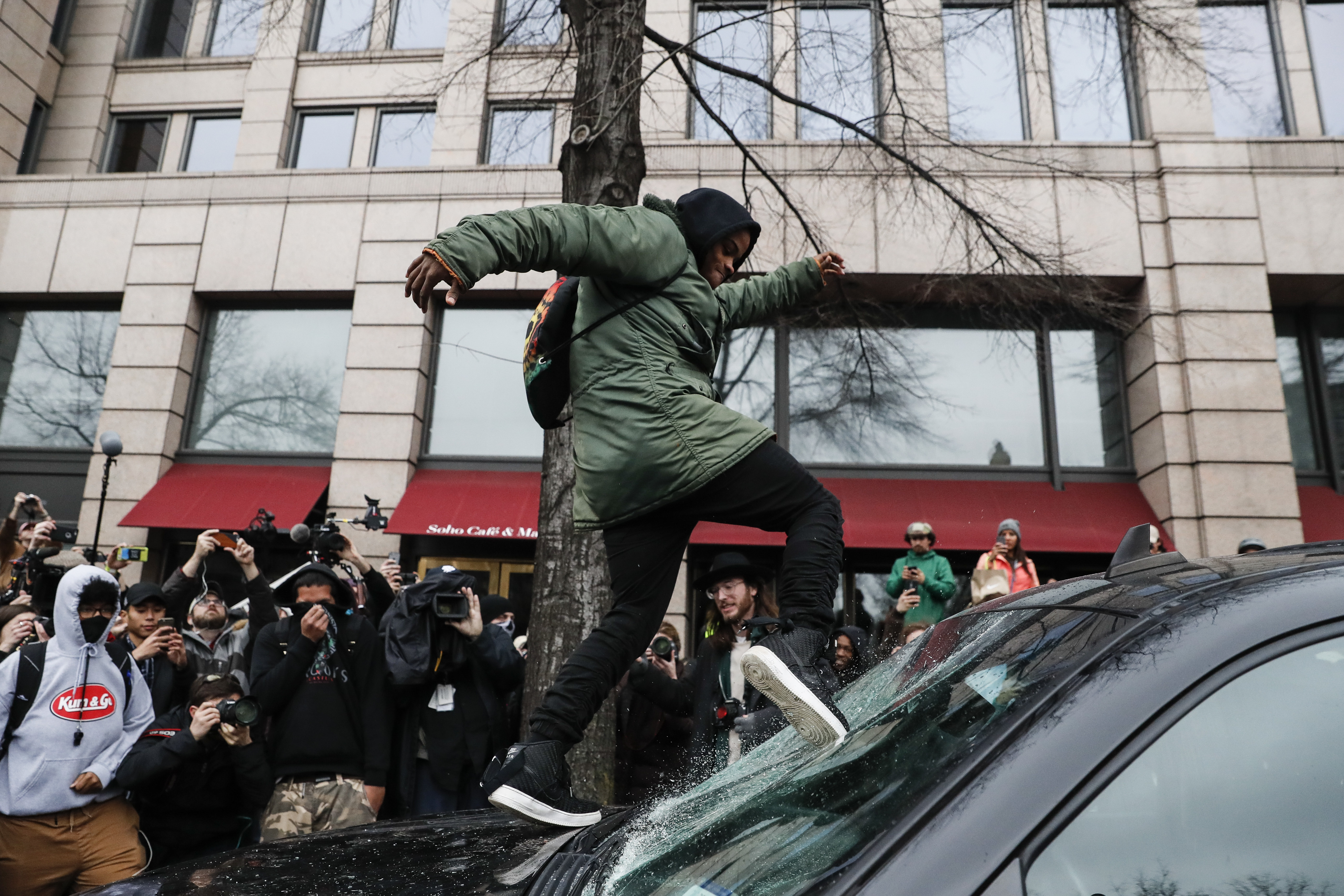 A protestor kicks in a windshield during a demonstration in Washington on Jan. 20, 2017, after the inauguration of President Donald Trump. (AP Photo/John Minchillo)