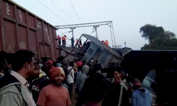 Rescuers and onlookers stand around coaches of a derailed passenger train in Kuneru, Andhra Pradesh, southern India, on Jan. 22, 2017. (KK Production via AP)