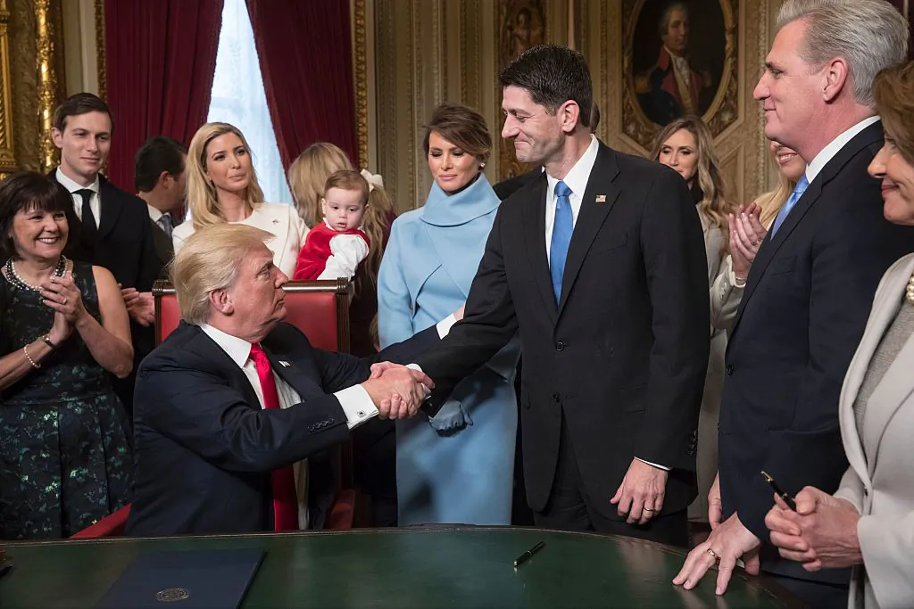 US President Donald Trump turns to House Speaker Paul Ryan as he is joined by the Congressional leadership and his family as he formally signs his cabinet nominations into law, in the President's Room of the Senate, at the Capitol in Washington,DC on Jan. 20, 2017.  
(J. SCOTT APPLEWHITE/AFP/Getty Images)