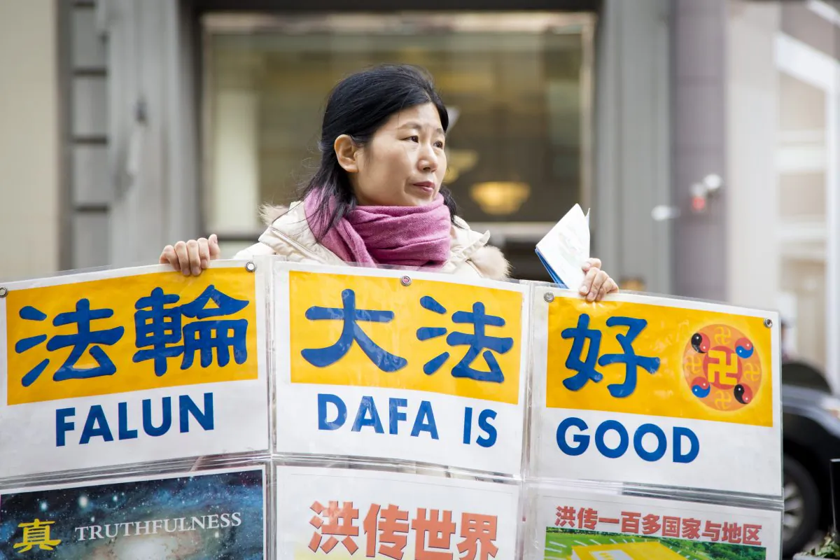 Wang Huijuan holds a display to help Chinese tourists understand the facts about the Chinese Communist Party's persecution of Falun Gong in China, in front of the Empire State Building in New York City on Jan. 12, 2017. (Samira Bouaou/Epoch Times)