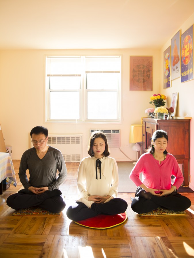 (L-R) Li Zhenjun, Li Fuyao, and Wang Huijuan demonstrate their meditation practice at their home in Queens, New York, on Jan. 8, 2016. They escaped China in 2014 and were granted asylum after years of torture for practicing Falun Gong. (Samira Bouaou/Epoch Times)