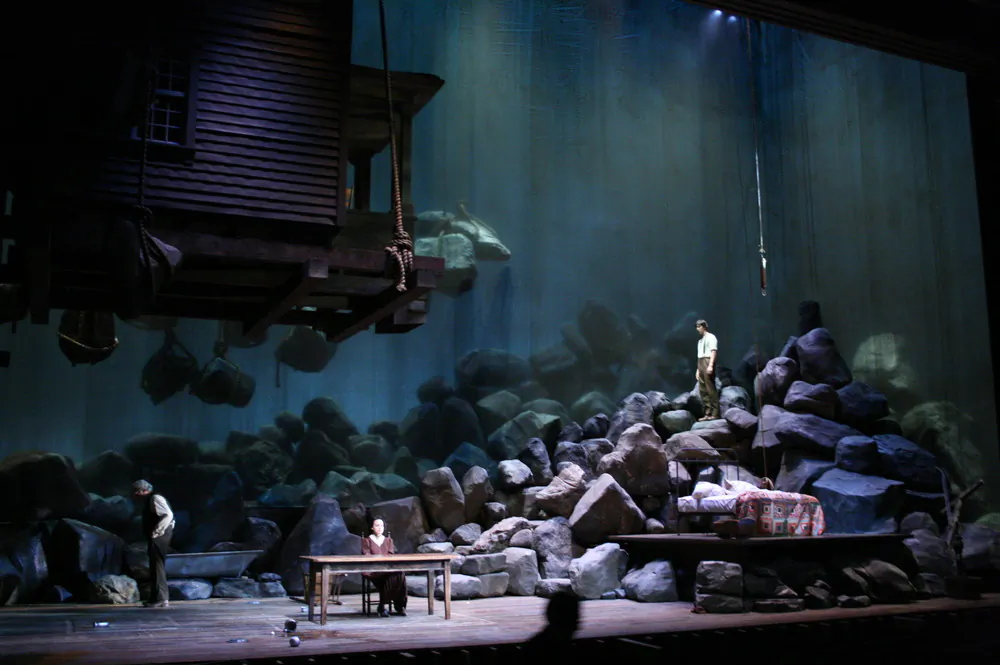 Using startling imagery of huge boulders and a whole house hoisted above the characters, Walt Spangler's set for "Desire Under the Elms" portends the doom resulting from heavy sins. (Courtesy of Walt Spangler)