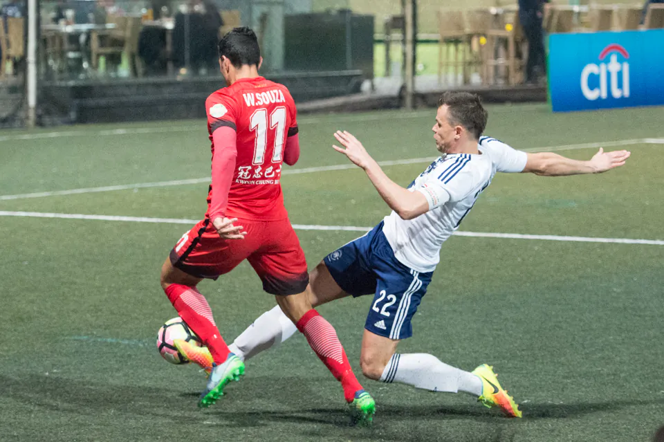 Wellingsson De Souza of Kwoon Chung Southern skips past this tackle by HKFC’s Gary Czechy during their 6-0 win in the HKFA Premier league at Sports Road on Friday Feb 3. 
Image Credit: (Bill Cox/Epoch Times)