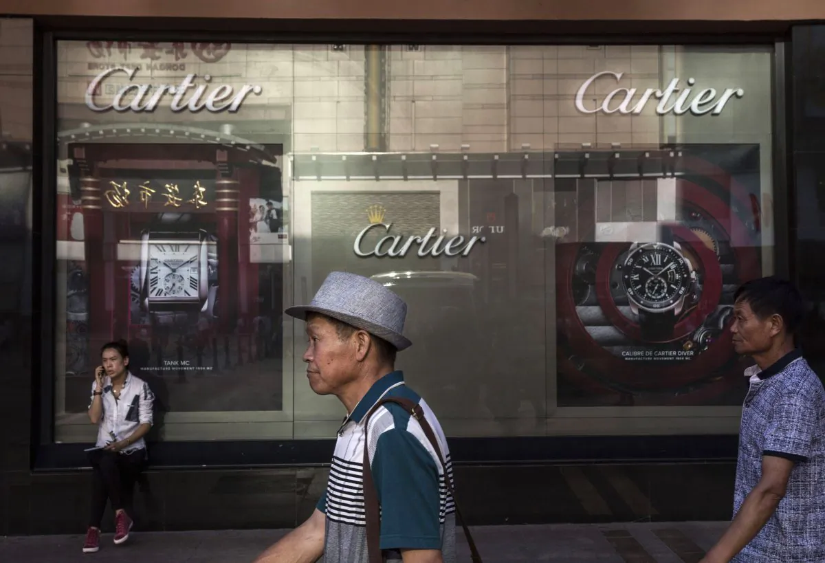 Shoppers walk pass a Cartier store in Beijing, Aug. 25, 2015. (Kevin Frayer/Getty Images)