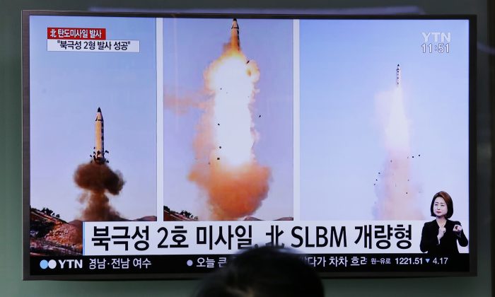 A man watches a TV news program showing photos published in North Korea's Rodong Sinmun newspaper of North Korea's 