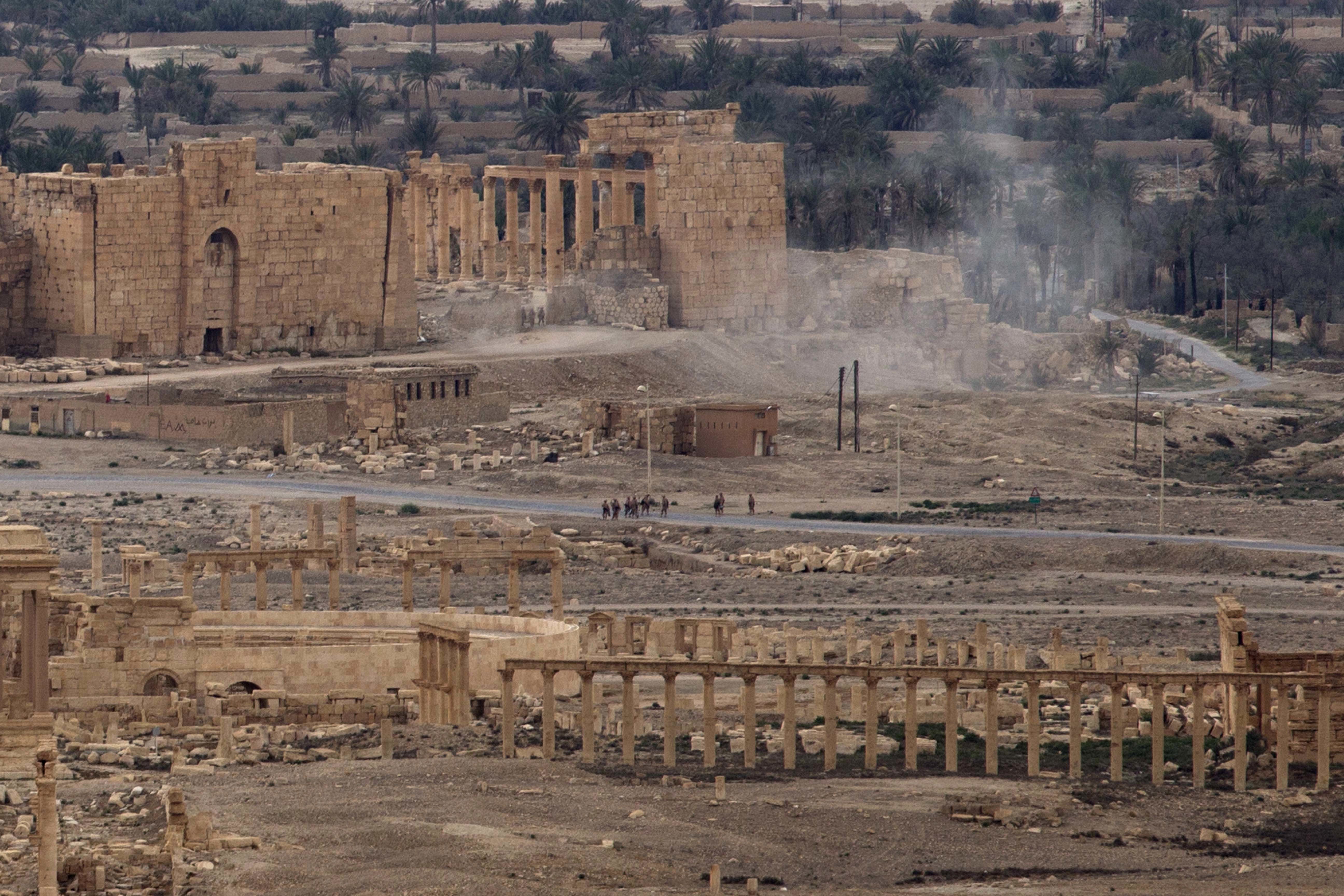 FILE -- In this April 14, 2016 file photo, Russian soldiers stand on a road as smoke rises from a controlled land mine detonation by Russian experts inside the ancient town of Palmyra, Syria in the central Homs province. Russia's defense ministry has released drone footage Monday, Feb. 13, 2017, showing new damage to Palmyra's archaeological site. The Islamic State group recaptured the ancient town in December from government troops, nine months after they were expelled in a Russia-backed offensive. The defense ministry said the footage was filmed earlier this month and showed a central section of Palmyra's famous theater lying in ruins. (AP Photo/Hassan Ammar, File)