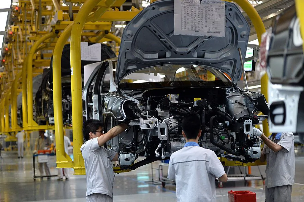 Chinese auto workers on the assembly line at the FAW-Volkswagen plant in Chengdu, southwest China's Sichuan province, during the visit of German Chancellor Angela Merkel on July 6, 2014. (GOH CHAI HIN/AFP/Getty Images)