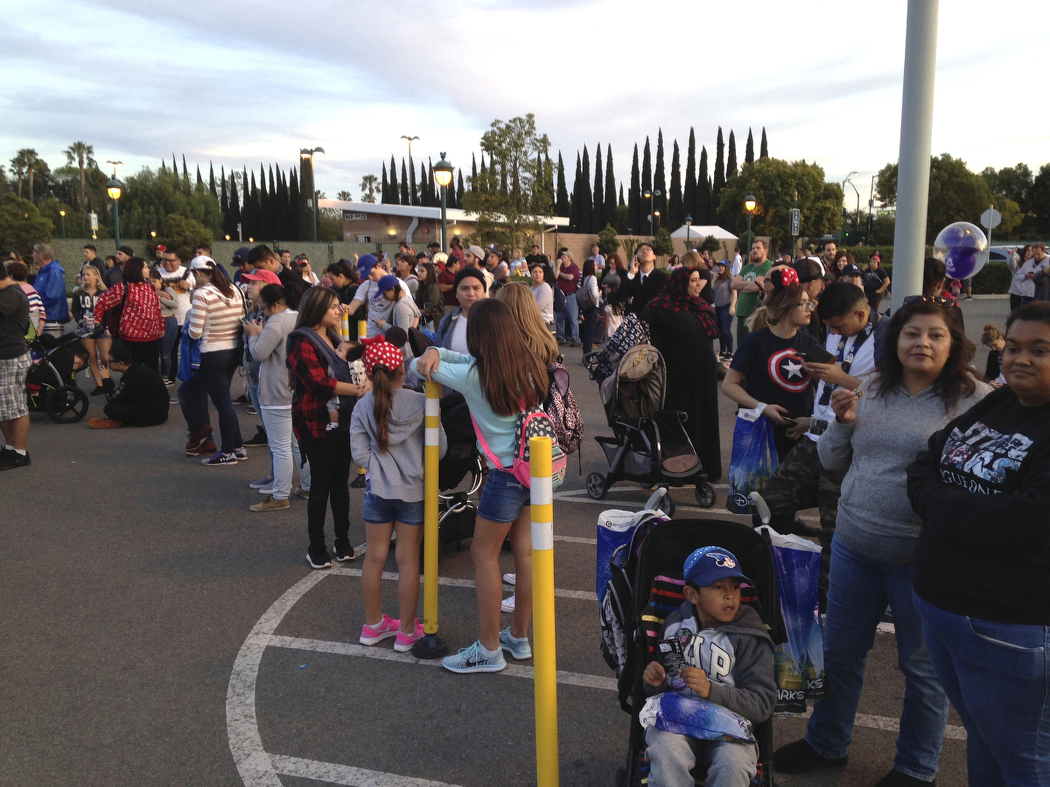 Disneyland visitors wait outside a parking garage after it was evacuated due to a fire in the garage in Anaheim, Calif., on Feb. 13, 2017. (Mark Eades/The Orange County Register via AP)