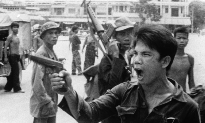 A Khmer Rouge soldier waves his pistol and orders store owners to abandon their shops in Phnom Penh, Cambodia, on April 17, 1975 as the capital fell to the communist forces. (AP Photo/Christoph Froehder)