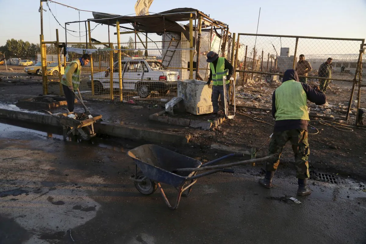 Baghdad municipality workers clean up the aftermath of a suicide car bomb attack at a used cars dealers parking lot in the eastern Habibiya neighborhood of Baghdad, Iraq on Feb. 16, 2017. (AP Photo/ Karim Kadim)