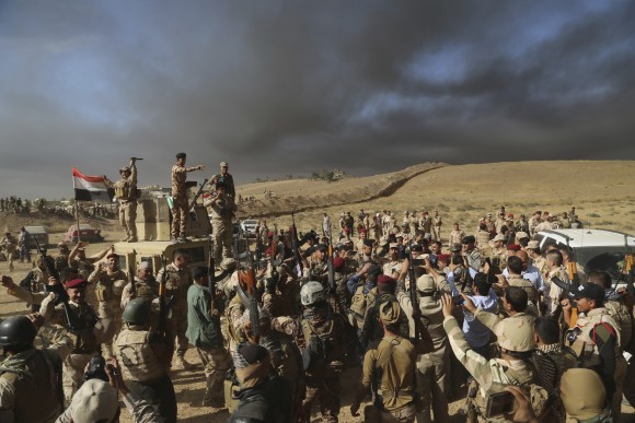 Iraqi army soldiers raise their weapons in celebration on the outskirts of Mosul, Iraq, in this Oct. 20, 2016 file photo. Iraqi special forces charged into the Mosul battle Thursday with a pre-dawn advance on the nearby town held by the Islamic State group, a key part of a multi-pronged assault on eastern approaches to the besieged city. (AP Photo, File)