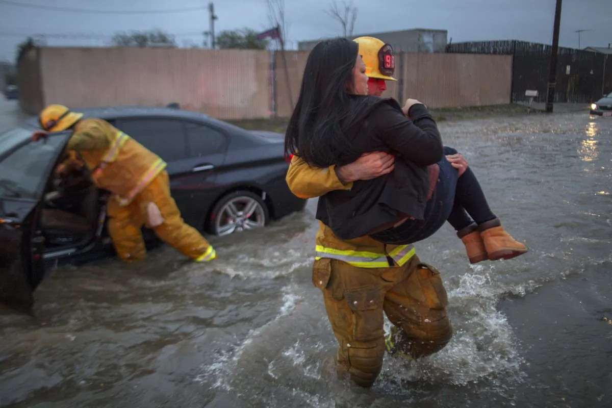 A firefighter carries a woman from her car after it was caught in street flooding as a powerful storm moved across Southern California in Sun Valley, Calif. on Feb. 17. (Photo by David McNew/Getty Images)
