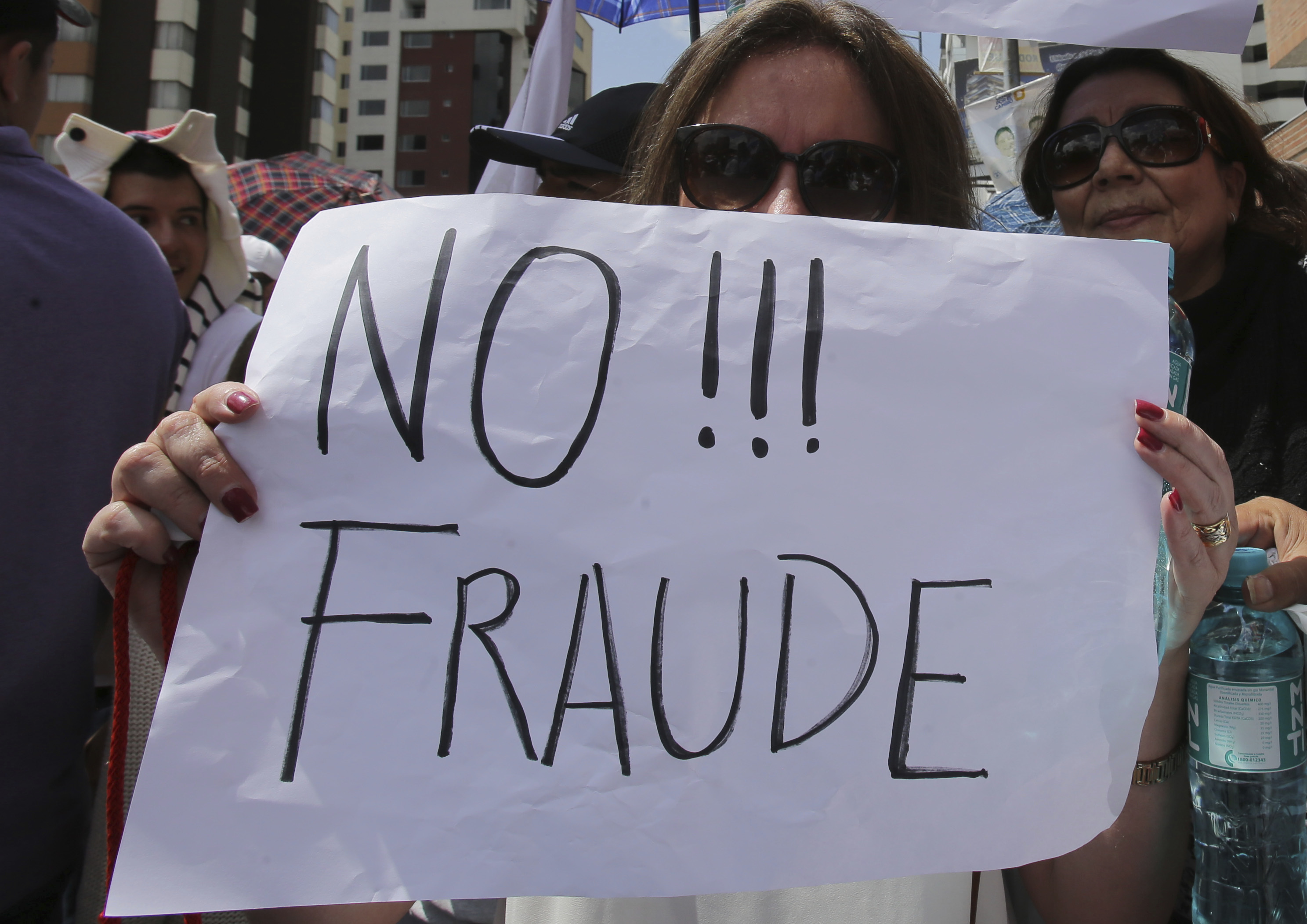 An opposition presidential candidate Guillermo Lasso's supporter holds a sign that read in Spanish "No to Fraud!" during protest outside Ecuador's National Electoral Council to demand the official results of the presidential elections, in Quito, Ecuador on Feb. 20, 2017. (AP Photo/Dolores Ochoa)