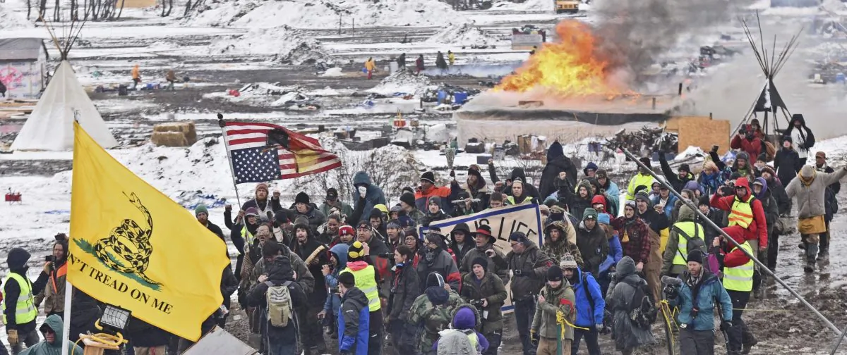 A fire set by protesters burns in the background as opponents of the Dakota Access pipeline leave their main protest camp near Cannon Ball, N.D., on Feb. 22, 2017. (Tom Stromme/The Bismarck Tribune/AP)